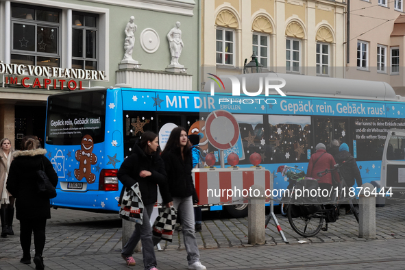 Festive decorations and shoppers appear during the holiday season in Augsburg, Bavaria, Germany, on December 14, 2024. A blue public bus wit...