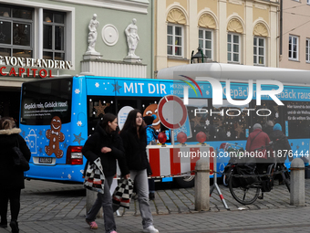 Festive decorations and shoppers appear during the holiday season in Augsburg, Bavaria, Germany, on December 14, 2024. A blue public bus wit...