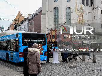 Festive decorations and shoppers appear during the holiday season in Augsburg, Bavaria, Germany, on December 14, 2024. A blue public bus wit...