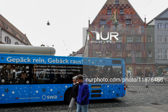 Festive decorations and shoppers appear during the holiday season in Augsburg, Bavaria, Germany, on December 14, 2024. A blue public bus wit...