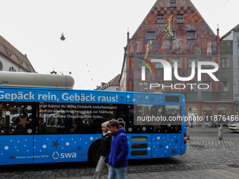 Festive decorations and shoppers appear during the holiday season in Augsburg, Bavaria, Germany, on December 14, 2024. A blue public bus wit...