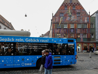 Festive decorations and shoppers appear during the holiday season in Augsburg, Bavaria, Germany, on December 14, 2024. A blue public bus wit...