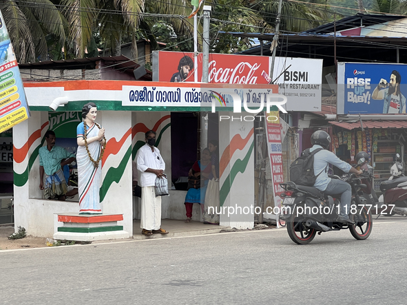 People wait at a bus stand near a statue of the former Prime Minister of India, Indira Gandhi, in Thiruvananthapuram, Kerala, India, on Apri...