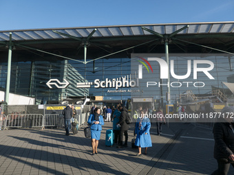 Entrance of Amsterdam Airport Schiphol AMS EHAM airport terminal with passenger and flight crew walking by and the logo inscription over the...