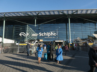 Entrance of Amsterdam Airport Schiphol AMS EHAM airport terminal with passenger and flight crew walking by and the logo inscription over the...