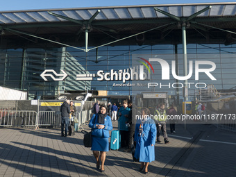 Entrance of Amsterdam Airport Schiphol AMS EHAM airport terminal with passenger and flight crew walking by and the logo inscription over the...