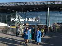 Entrance of Amsterdam Airport Schiphol AMS EHAM airport terminal with passenger and flight crew walking by and the logo inscription over the...