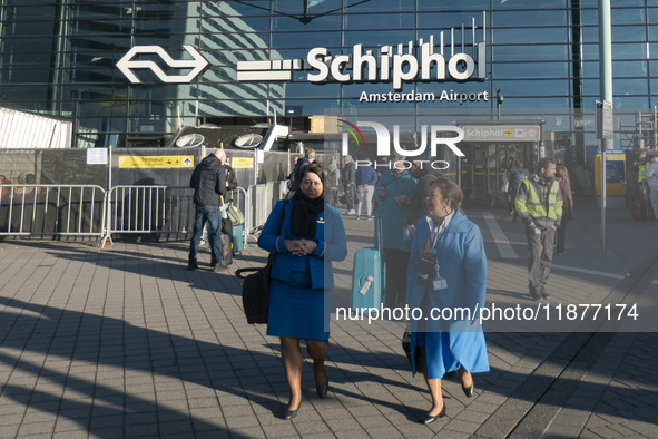 Entrance of Amsterdam Airport Schiphol AMS EHAM airport terminal with passenger and flight crew walking by and the logo inscription over the...