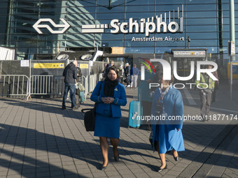 Entrance of Amsterdam Airport Schiphol AMS EHAM airport terminal with passenger and flight crew walking by and the logo inscription over the...