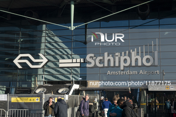 Entrance of Amsterdam Airport Schiphol AMS EHAM airport terminal with passenger and flight crew walking by and the logo inscription over the...