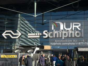 Entrance of Amsterdam Airport Schiphol AMS EHAM airport terminal with passenger and flight crew walking by and the logo inscription over the...