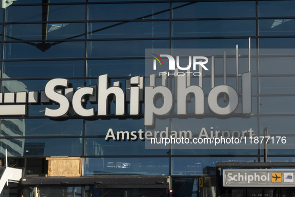 Entrance of Amsterdam Airport Schiphol AMS EHAM airport terminal with passenger and flight crew walking by and the logo inscription over the...