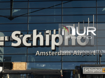 Entrance of Amsterdam Airport Schiphol AMS EHAM airport terminal with passenger and flight crew walking by and the logo inscription over the...