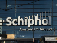 Entrance of Amsterdam Airport Schiphol AMS EHAM airport terminal with passenger and flight crew walking by and the logo inscription over the...