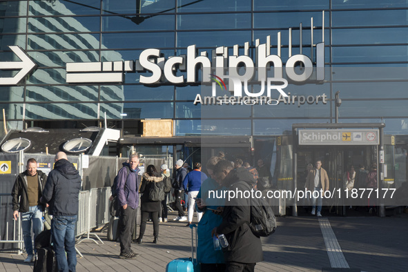 Entrance of Amsterdam Airport Schiphol AMS EHAM airport terminal with passenger and flight crew walking by and the logo inscription over the...