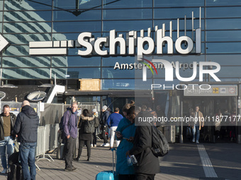 Entrance of Amsterdam Airport Schiphol AMS EHAM airport terminal with passenger and flight crew walking by and the logo inscription over the...