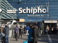 Entrance of Amsterdam Airport Schiphol AMS EHAM airport terminal with passenger and flight crew walking by and the logo inscription over the...