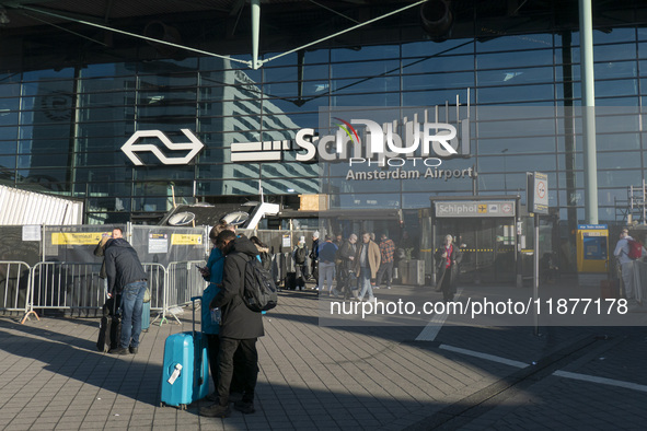 Entrance of Amsterdam Airport Schiphol AMS EHAM airport terminal with passenger and flight crew walking by and the logo inscription over the...