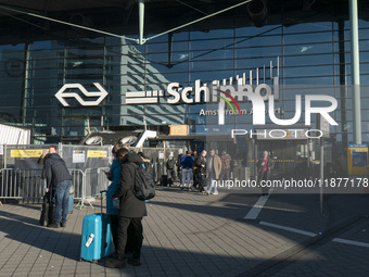 Entrance of Amsterdam Airport Schiphol AMS EHAM airport terminal with passenger and flight crew walking by and the logo inscription over the...