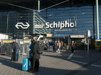 Entrance of Amsterdam Airport Schiphol AMS EHAM airport terminal with passenger and flight crew walking by and the logo inscription over the...