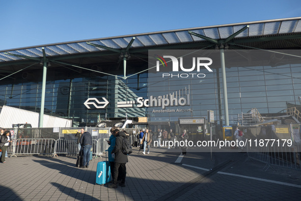 Entrance of Amsterdam Airport Schiphol AMS EHAM airport terminal with passenger and flight crew walking by and the logo inscription over the...