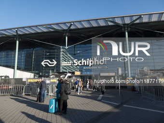 Entrance of Amsterdam Airport Schiphol AMS EHAM airport terminal with passenger and flight crew walking by and the logo inscription over the...