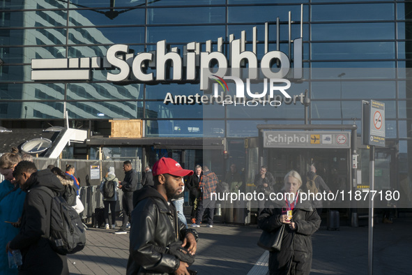 Entrance of Amsterdam Airport Schiphol AMS EHAM airport terminal with passenger and flight crew walking by and the logo inscription over the...