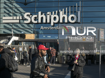 Entrance of Amsterdam Airport Schiphol AMS EHAM airport terminal with passenger and flight crew walking by and the logo inscription over the...