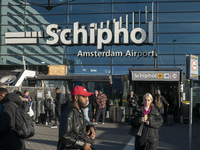 Entrance of Amsterdam Airport Schiphol AMS EHAM airport terminal with passenger and flight crew walking by and the logo inscription over the...