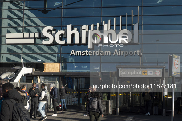 Entrance of Amsterdam Airport Schiphol AMS EHAM airport terminal with passenger and flight crew walking by and the logo inscription over the...