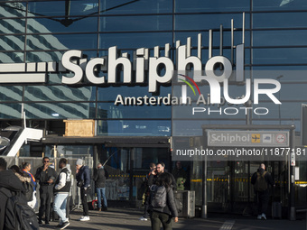 Entrance of Amsterdam Airport Schiphol AMS EHAM airport terminal with passenger and flight crew walking by and the logo inscription over the...