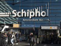 Entrance of Amsterdam Airport Schiphol AMS EHAM airport terminal with passenger and flight crew walking by and the logo inscription over the...