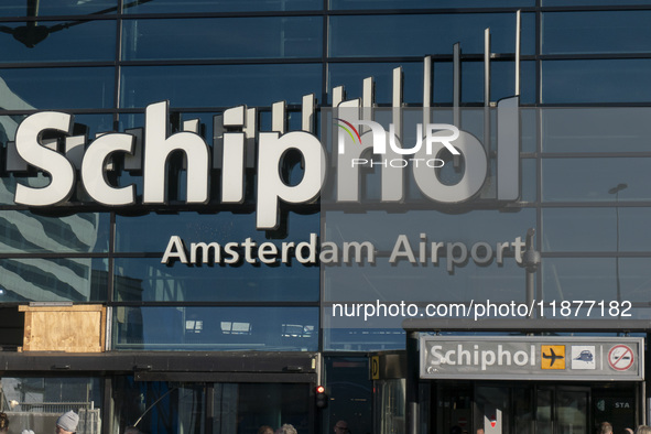 Entrance of Amsterdam Airport Schiphol AMS EHAM airport terminal with passenger and flight crew walking by and the logo inscription over the...