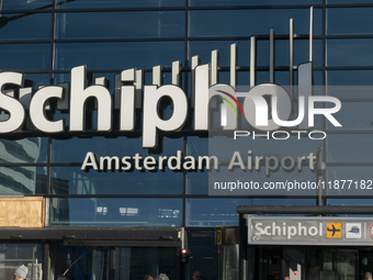 Entrance of Amsterdam Airport Schiphol AMS EHAM airport terminal with passenger and flight crew walking by and the logo inscription over the...