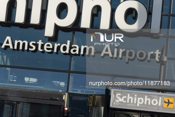 Entrance of Amsterdam Airport Schiphol AMS EHAM airport terminal with passenger and flight crew walking by and the logo inscription over the...