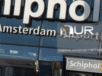 Entrance of Amsterdam Airport Schiphol AMS EHAM airport terminal with passenger and flight crew walking by and the logo inscription over the...