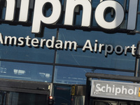 Entrance of Amsterdam Airport Schiphol AMS EHAM airport terminal with passenger and flight crew walking by and the logo inscription over the...