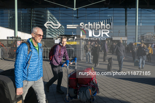 Entrance of Amsterdam Airport Schiphol AMS EHAM airport terminal with passenger and flight crew walking by and the logo inscription over the...