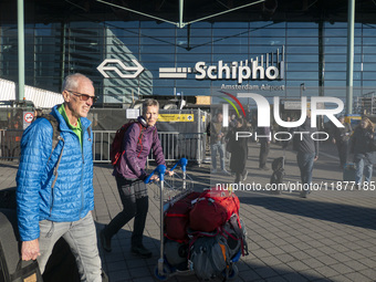 Entrance of Amsterdam Airport Schiphol AMS EHAM airport terminal with passenger and flight crew walking by and the logo inscription over the...