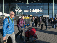 Entrance of Amsterdam Airport Schiphol AMS EHAM airport terminal with passenger and flight crew walking by and the logo inscription over the...