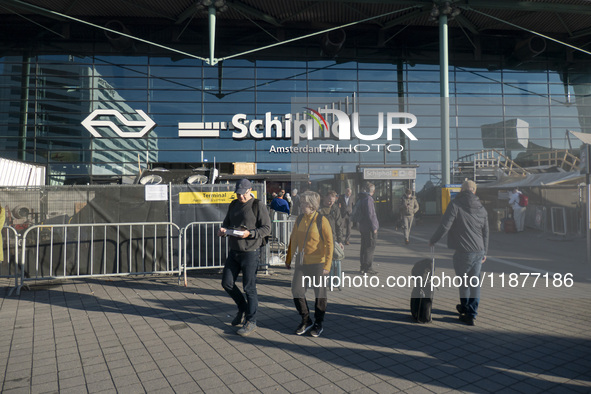 Entrance of Amsterdam Airport Schiphol AMS EHAM airport terminal with passenger and flight crew walking by and the logo inscription over the...