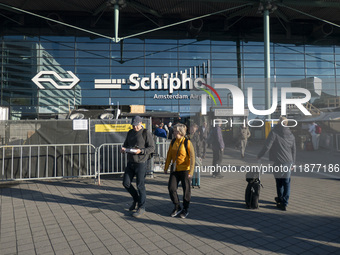 Entrance of Amsterdam Airport Schiphol AMS EHAM airport terminal with passenger and flight crew walking by and the logo inscription over the...