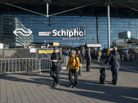 Entrance of Amsterdam Airport Schiphol AMS EHAM airport terminal with passenger and flight crew walking by and the logo inscription over the...