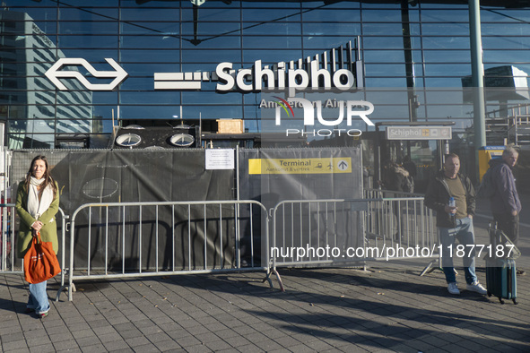 Entrance of Amsterdam Airport Schiphol AMS EHAM airport terminal with passenger and flight crew walking by and the logo inscription over the...