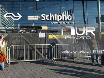 Entrance of Amsterdam Airport Schiphol AMS EHAM airport terminal with passenger and flight crew walking by and the logo inscription over the...