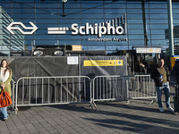 Entrance of Amsterdam Airport Schiphol AMS EHAM airport terminal with passenger and flight crew walking by and the logo inscription over the...