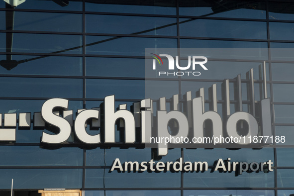 Entrance of Amsterdam Airport Schiphol AMS EHAM airport terminal with passenger and flight crew walking by and the logo inscription over the...