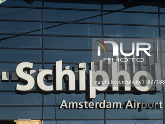 Entrance of Amsterdam Airport Schiphol AMS EHAM airport terminal with passenger and flight crew walking by and the logo inscription over the...