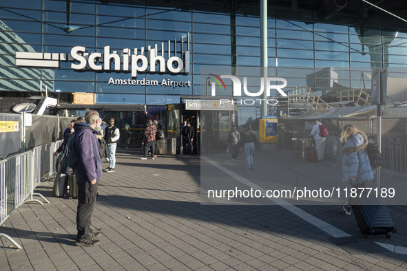 Entrance of Amsterdam Airport Schiphol AMS EHAM airport terminal with passenger and flight crew walking by and the logo inscription over the...