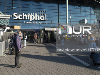 Entrance of Amsterdam Airport Schiphol AMS EHAM airport terminal with passenger and flight crew walking by and the logo inscription over the...